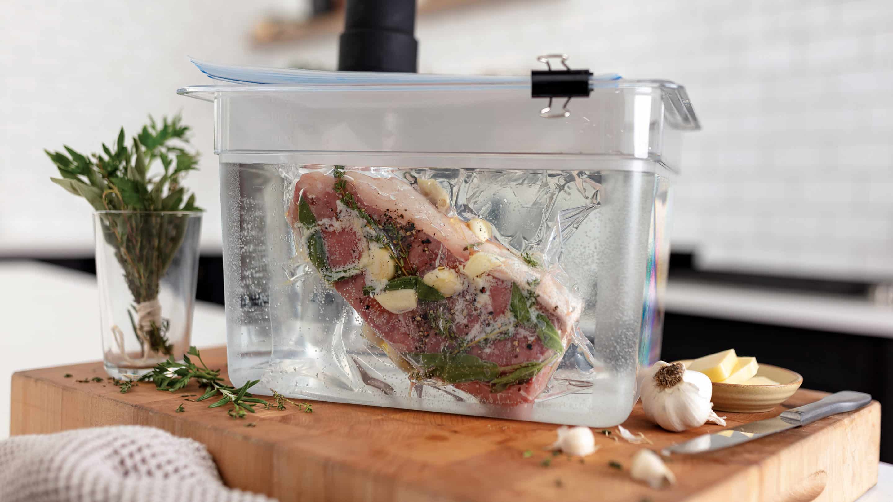 Meat in a plastic bag being submerged in water to be cooked